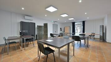 A conference room with tables, chairs, a projector, and a whiteboard.