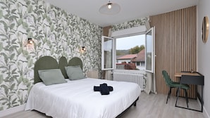 Een slaapkamer met een bed, een bureau, een stoel, een radiator en een raam met vrij uitzicht.