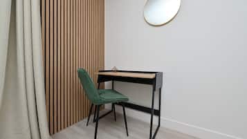 Una habitación con pared de listones de madera, un escritorio con silla y un espejo redondo en la pared.