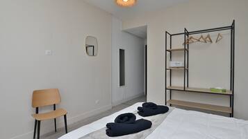 A bedroom with a bed, a chair, a wardrobe, and a mirror.