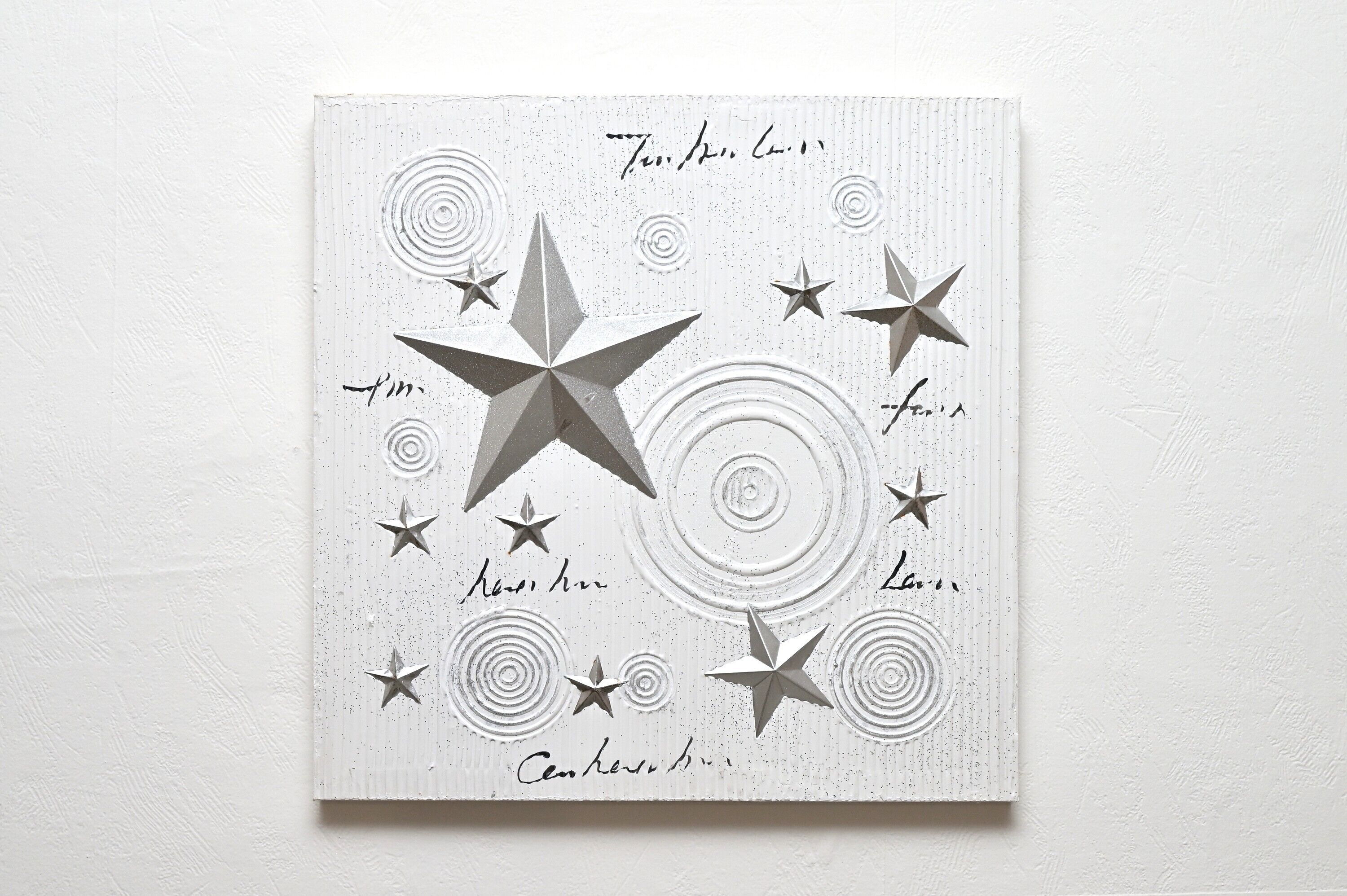 A white wall with a textured pattern and several stars of varying sizes.