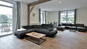 A modern living room with a sectional sofa, a coffee table, and a dining area with chairs.