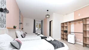 A hotel room with two beds, a wardrobe, a heater, and a window with curtains.