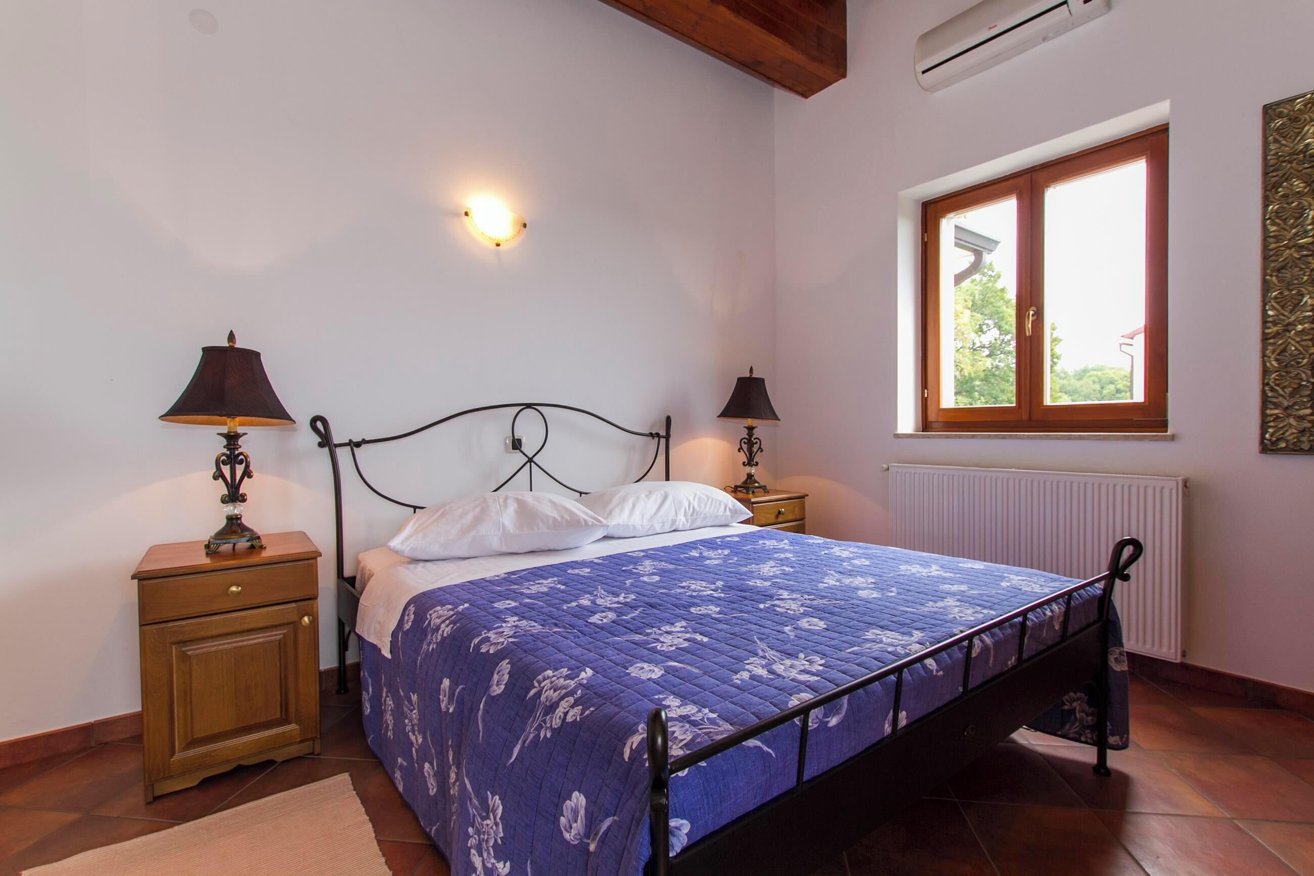 Een slaapkamer met een bed, twee nachtkastjes, een wandlamp en een raam met uitzicht.