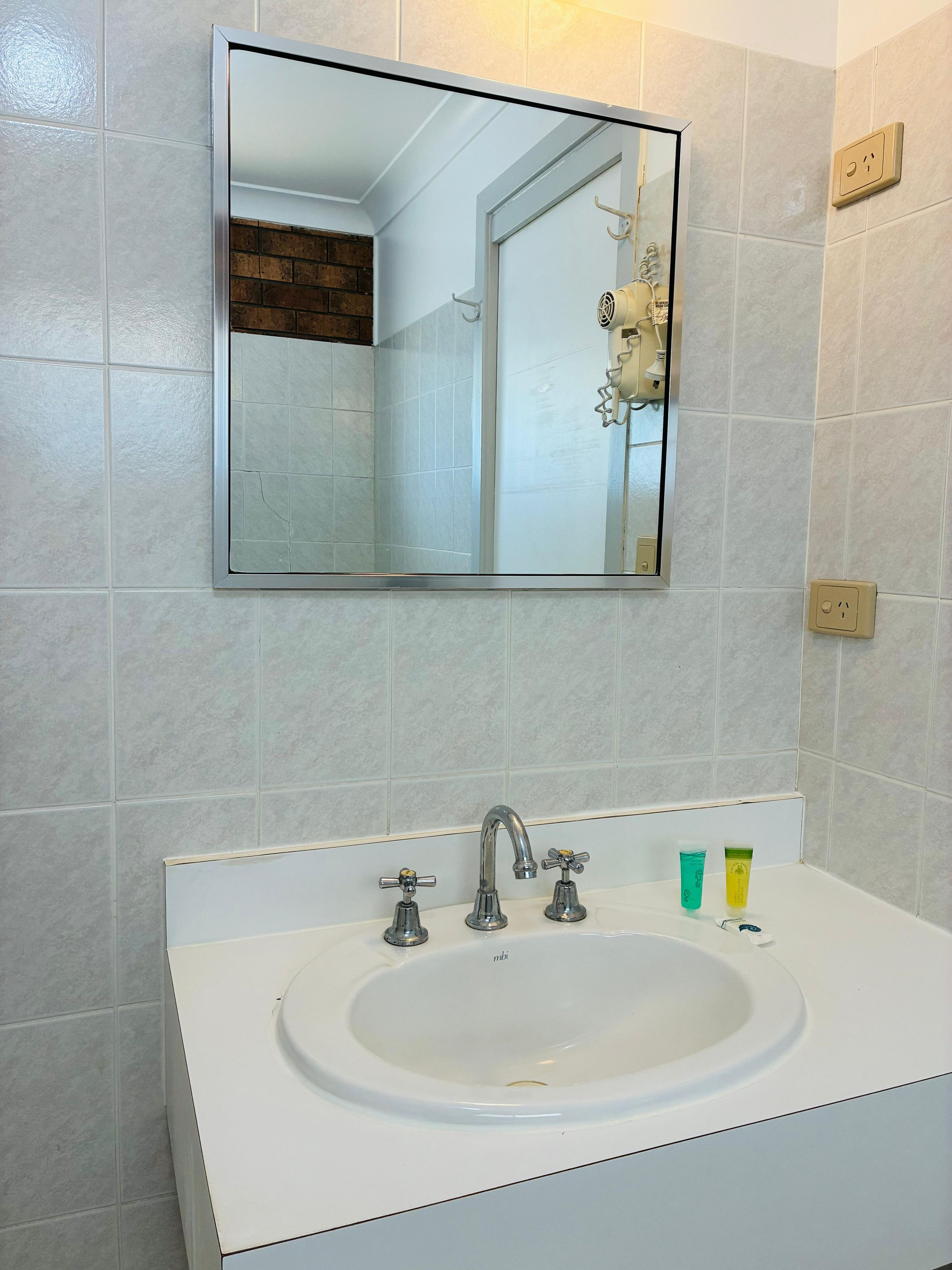 A bathroom with a white sink, a mirror, and a towel rack.