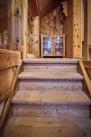 Eine Holztreppe führt zu einem Glastischschrank.