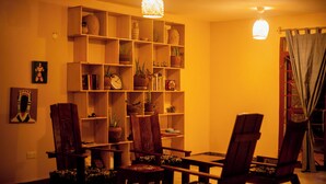 Un coin repas avec des chaises en bois et une table, entouré d’étagères où sont disposées des plantes en pot et des livres.