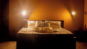 Une chambre à coucher faiblement éclairée, avec un lit, des oreillers et une table de chevet.