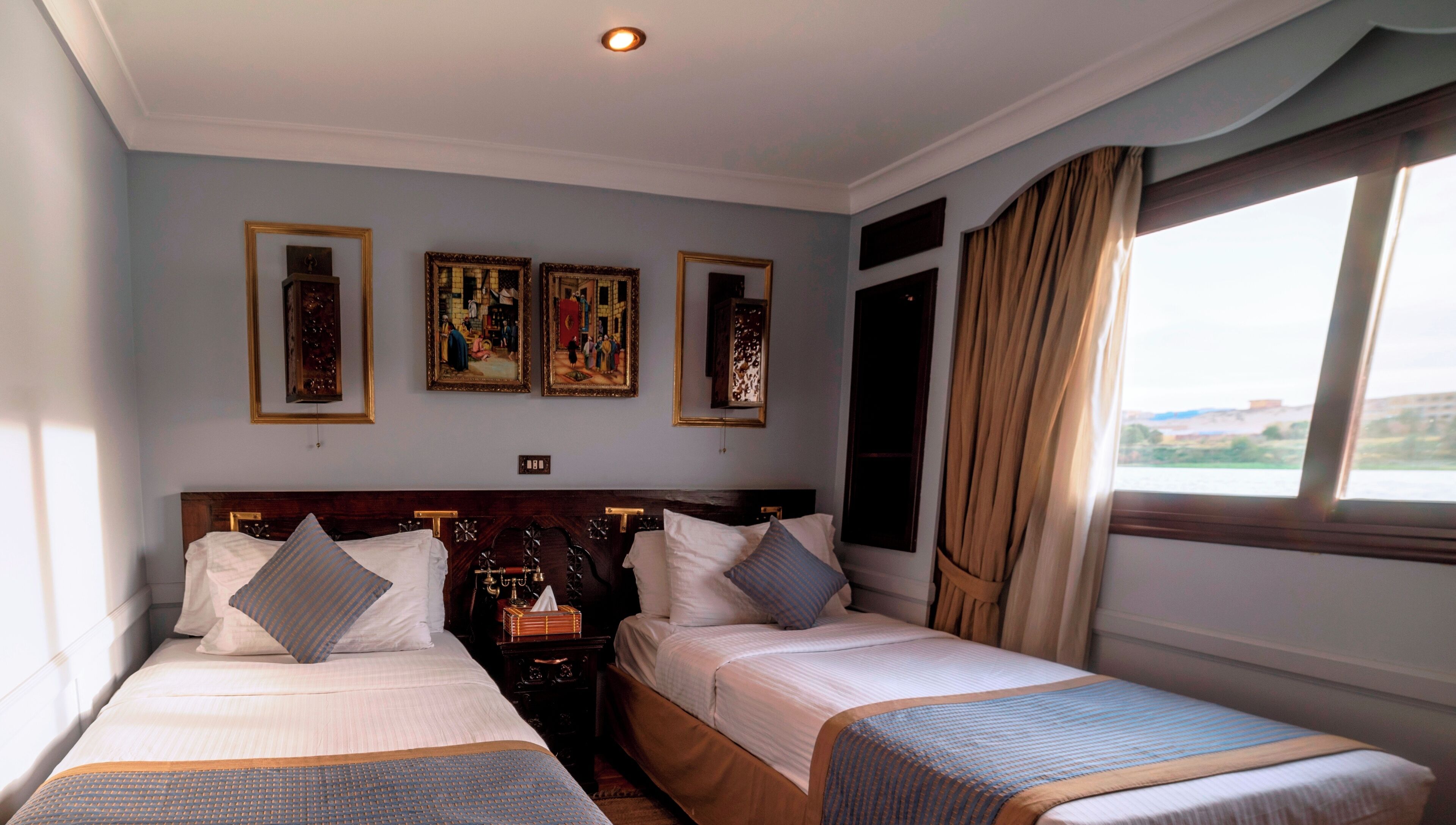 Ein Hotelzimmer mit zwei Betten, einem Nachttisch und drei gerahmten Kunstwerken an der Wand.