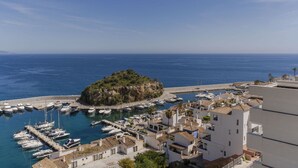 A coastal town with a marina, white buildings, and a small island with greenery. - RentitSpain – Sea Views, Pool & Private Beach (Granada)
