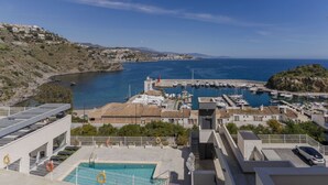 A coastal view with a marina, a swimming pool, and buildings with Mediterranean architecture. - RentitSpain – Sea Views, Pool & Private Beach (Granada)
