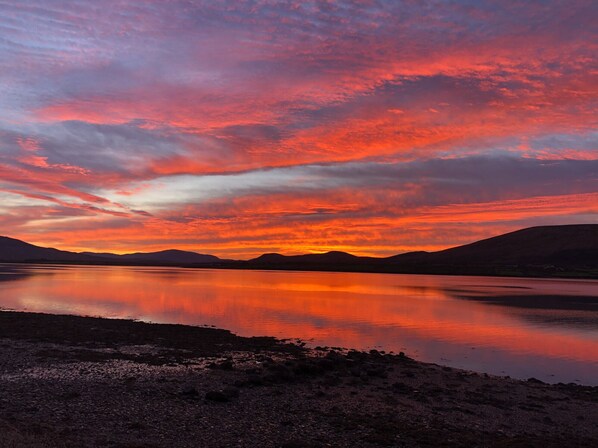 A sunset over a calm lake with mountains in the background.