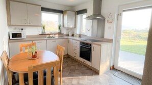 A modern kitchen with a dining area, large windows, and a view of the countryside.