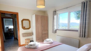 A bedroom with a bed, a wardrobe, a window with curtains, a radiator, and a mirror on the wall.