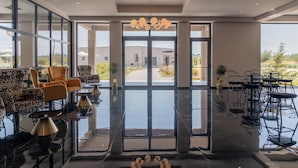 Un vestíbulo amplio con suelo reflectante, muebles modernos y grandes ventanales que ofrecen vistas al exterior.