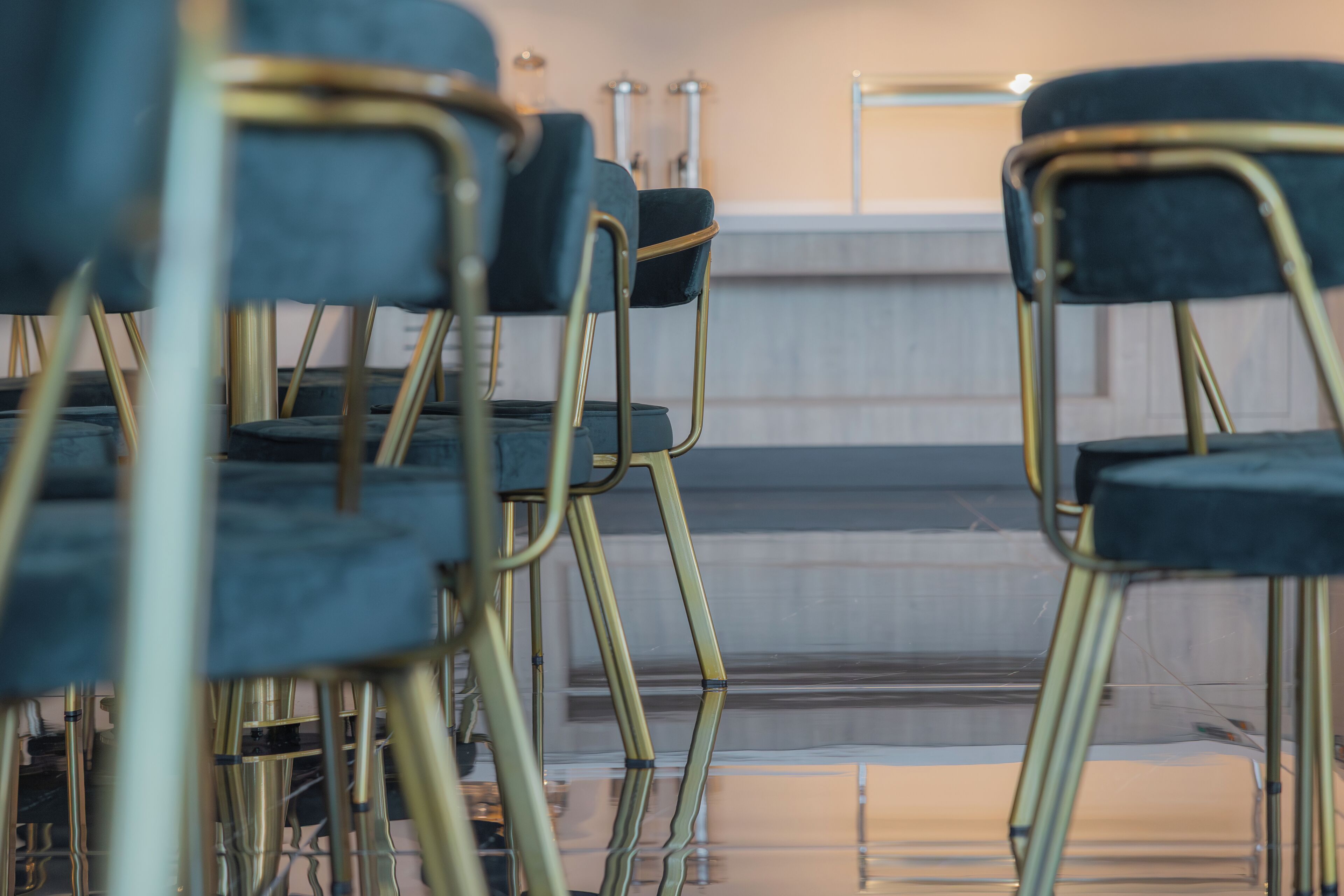 Rows of black chairs with gold frames in a room with a reflective floor and a neutral-colored wall.