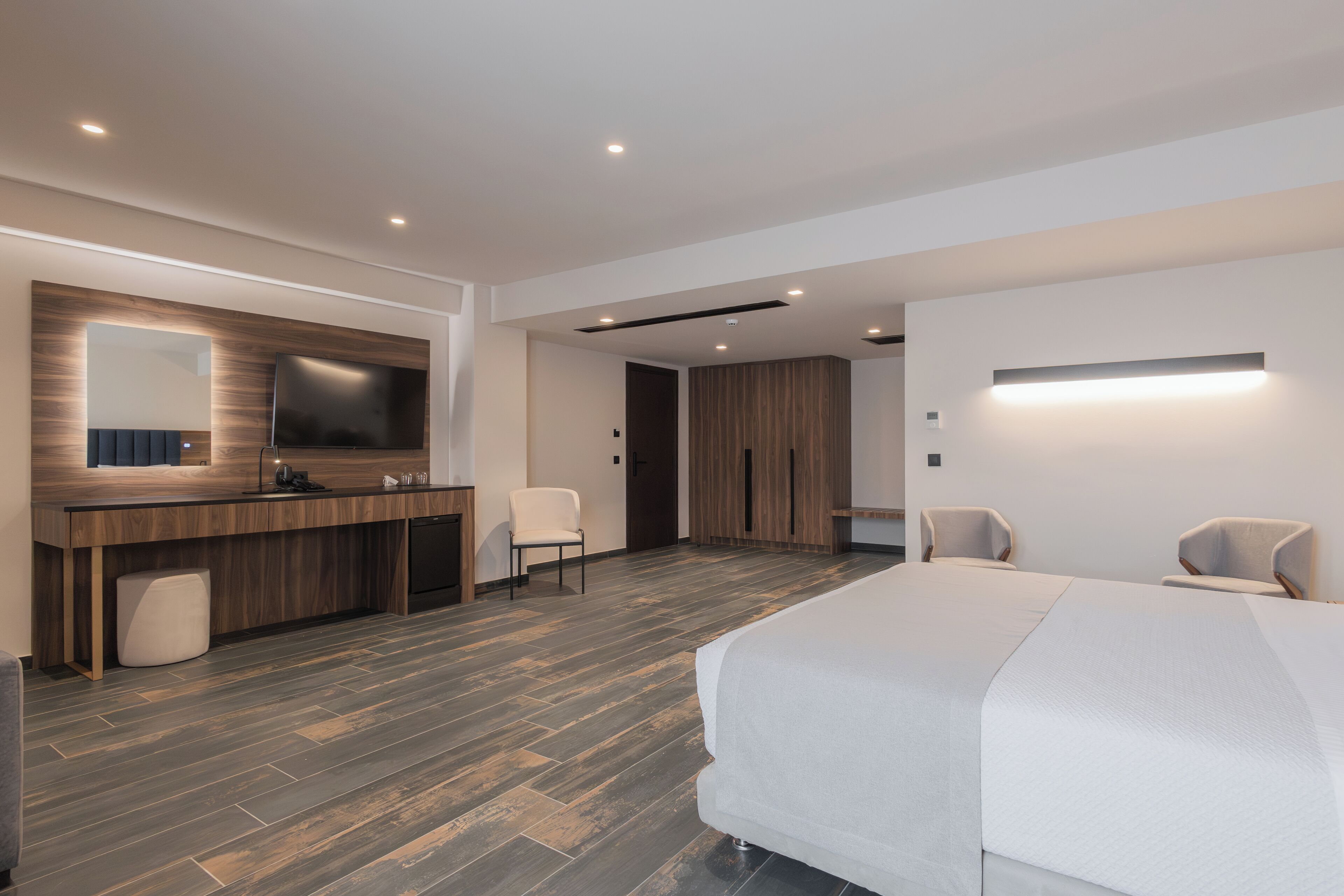 Une chambre d’hôtel moderne dotée d’un grand lit, d’un bureau avec un téléviseur à écran plat, d’une chaise et d’une armoire.
