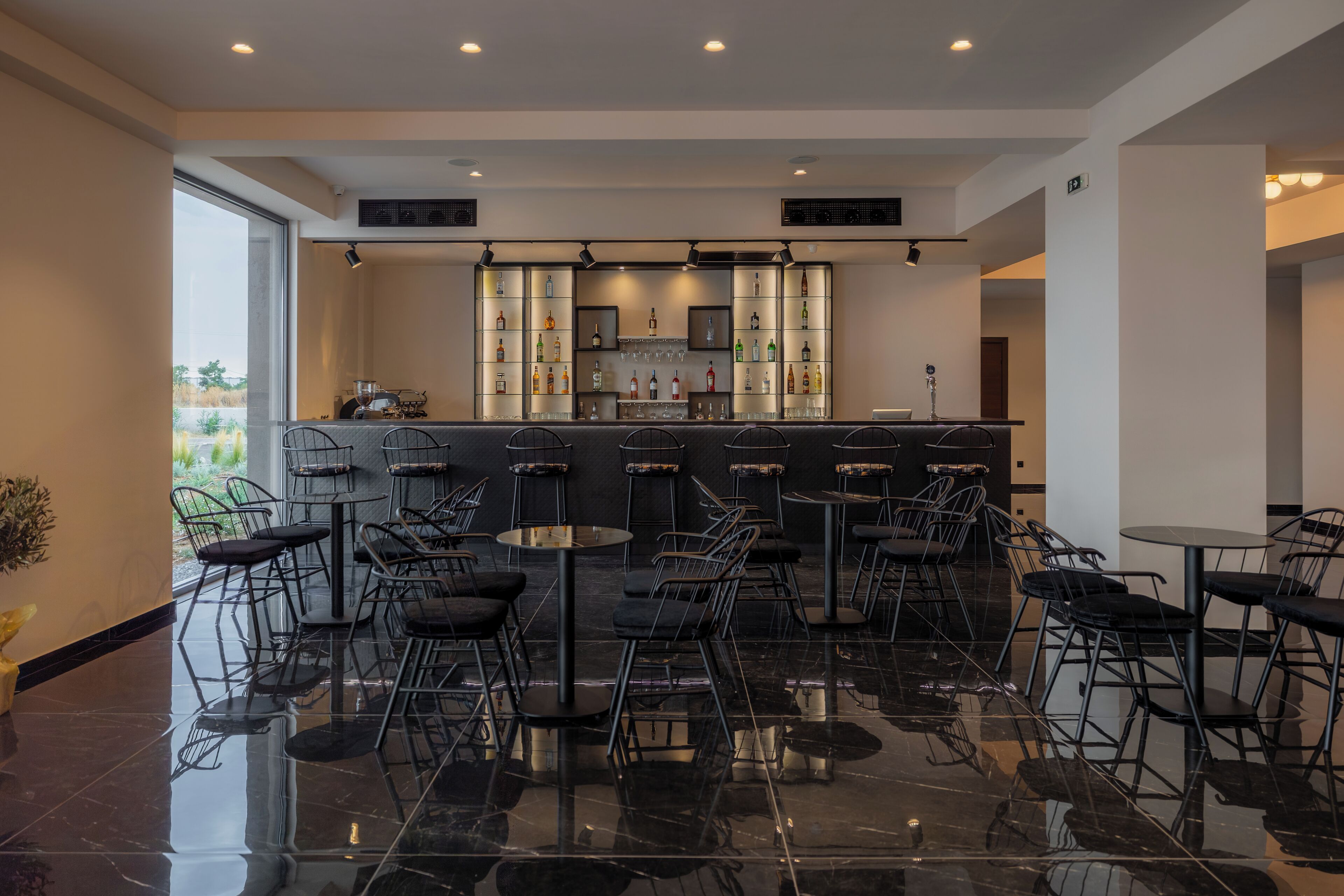 Un bar moderno con piso pulido, varios arreglos de asientos y un interior bien iluminado.
