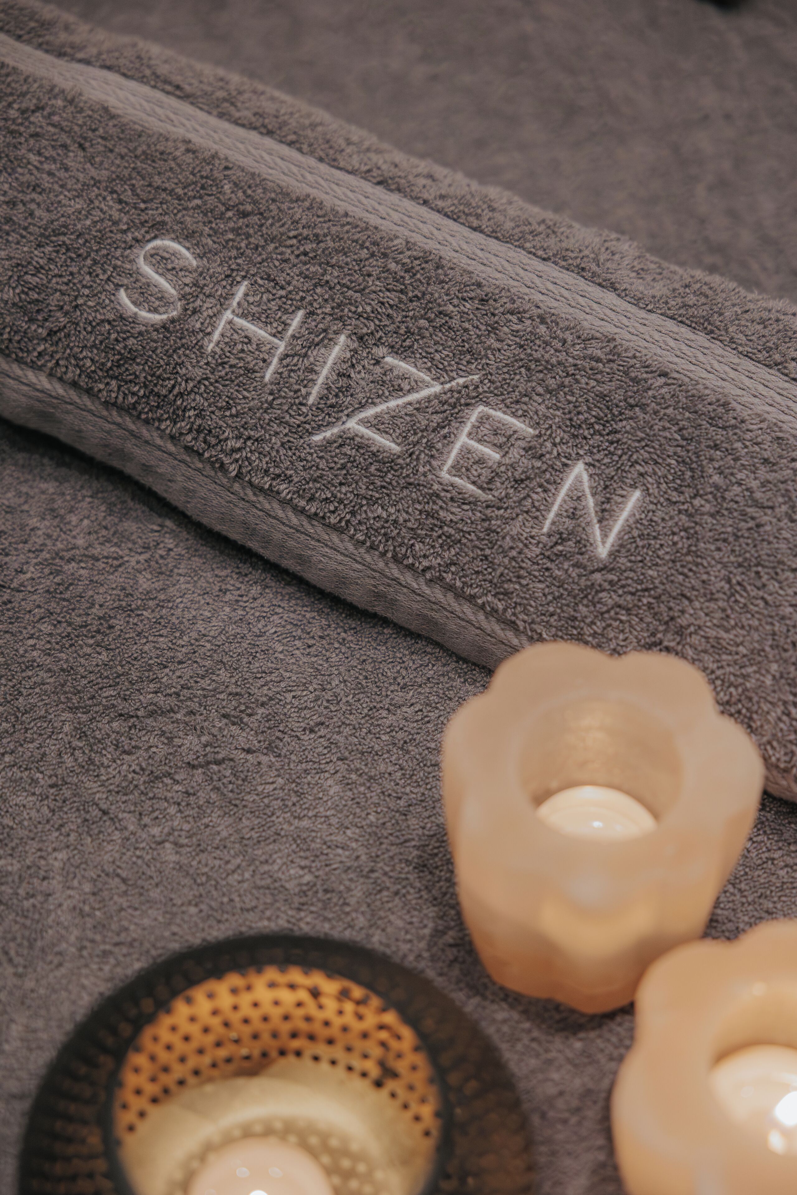 Ein grau strukturiertes Handtuch mit dem Aufdruck 'SHIZEN'.