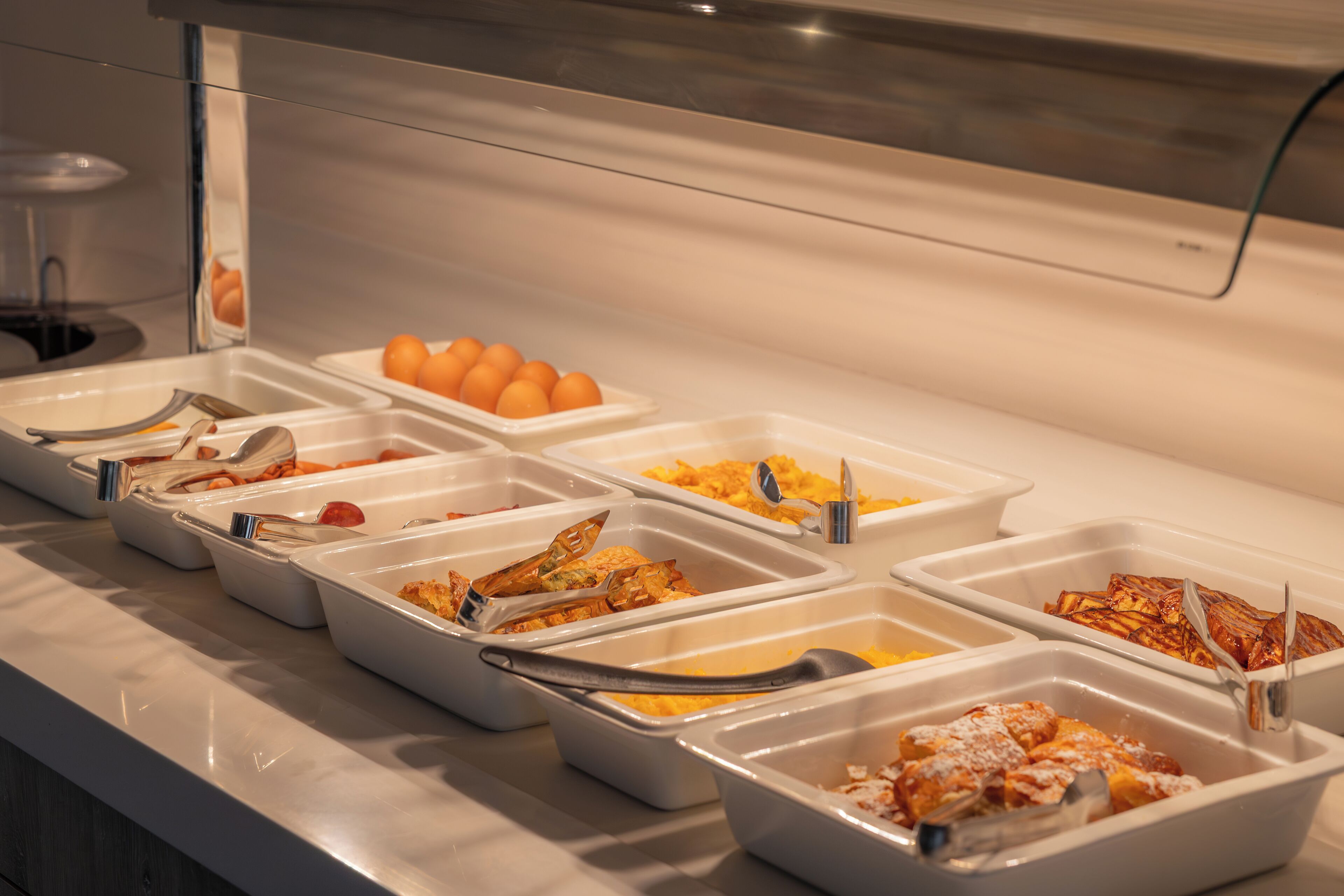 A buffet with various food options, including eggs, scrambled eggs, and other dishes.