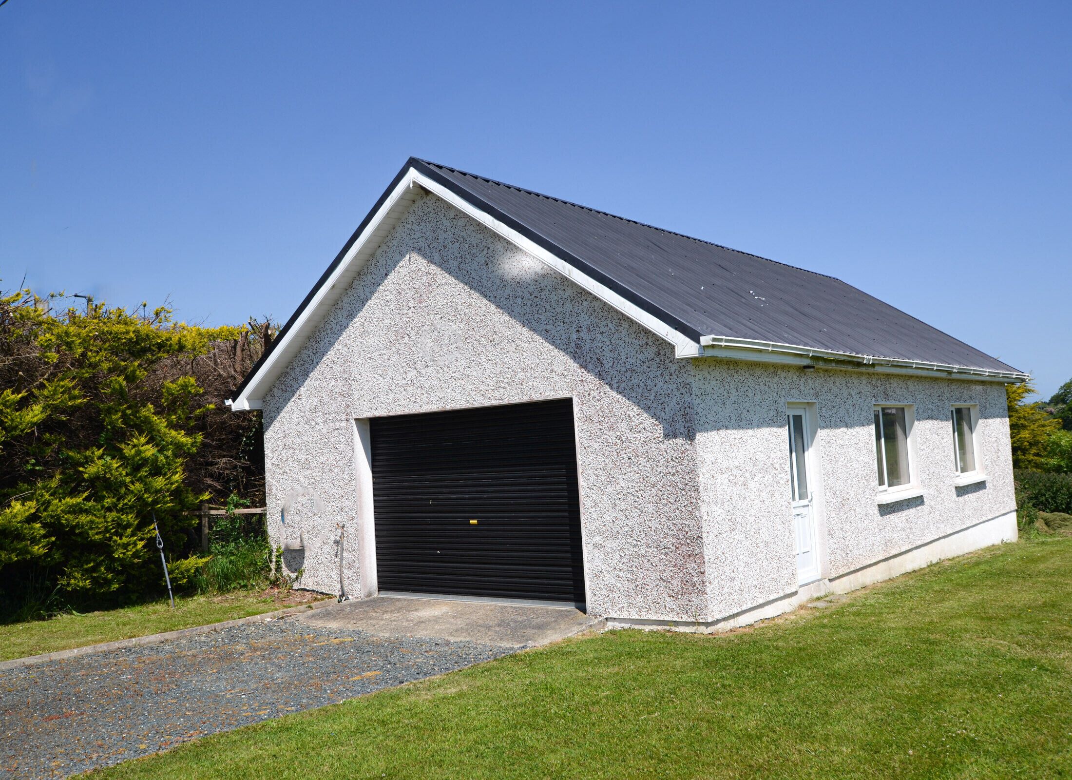 A single-story building with a sloped roof, a garage door, and a small window.