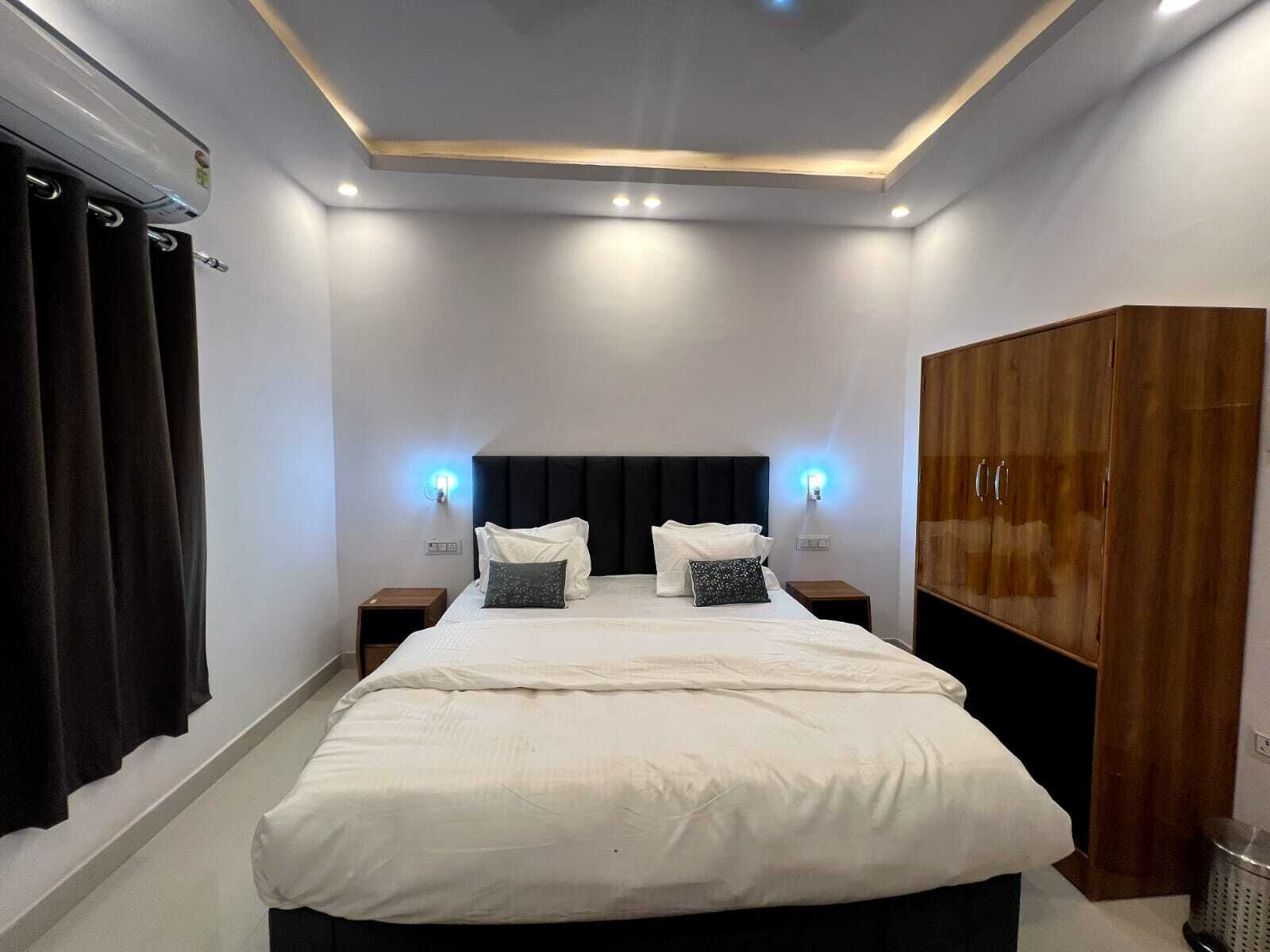 Un dormitorio moderno con una cama grande, dos mesitas de noche, un armario e iluminación empotrada en el techo.