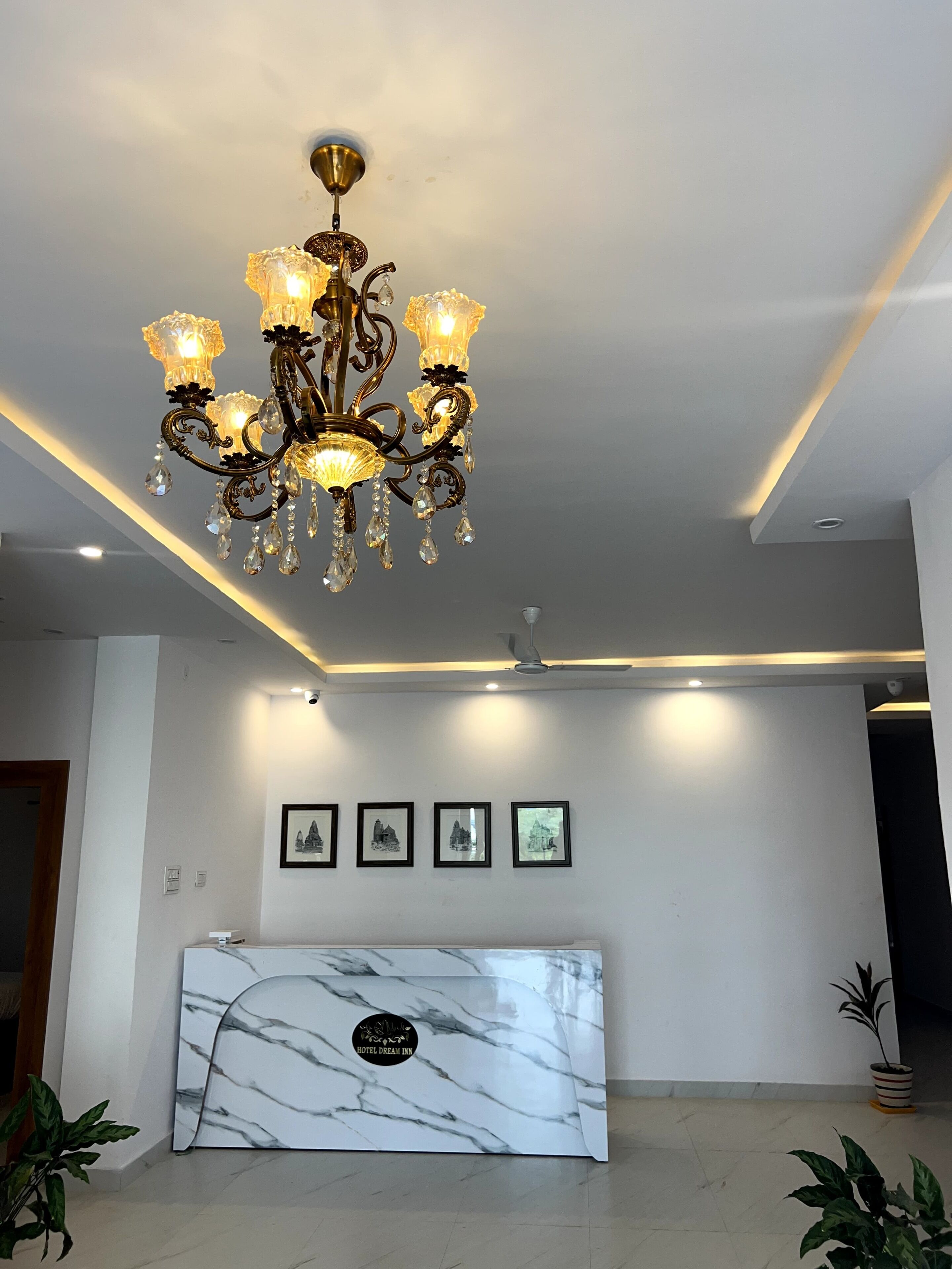 Una recepción con encimera de mármol, una araña de cristal y cuadros enmarcados en la pared.