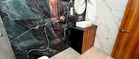 A bathroom with a marble wall, a wooden cabinet, a sink, a toilet, and a shower.