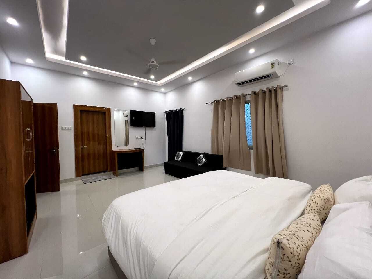 Un dormitorio moderno con una cama grande, un armario, un tocador, un televisor de pantalla plana y un aire acondicionado.