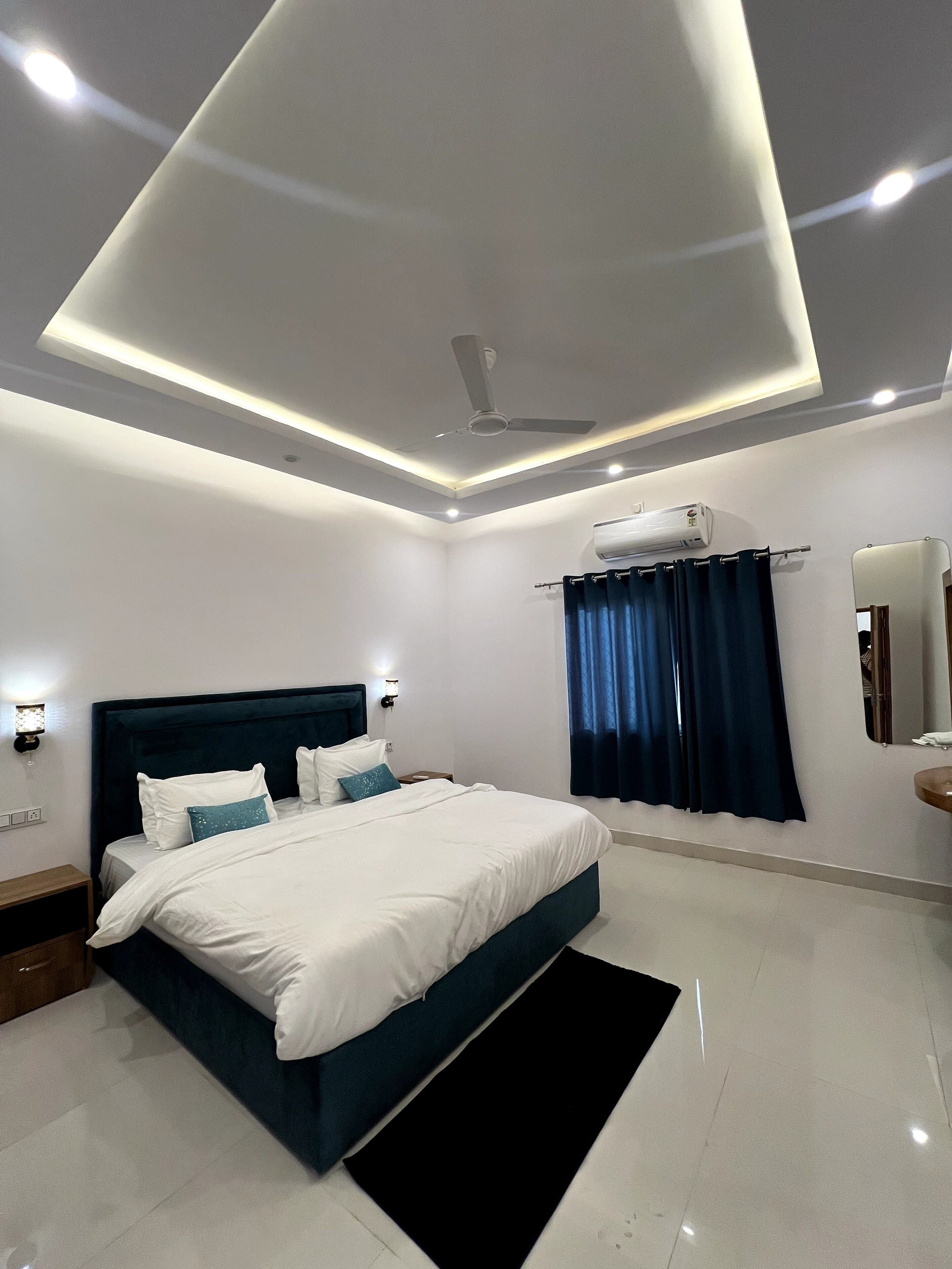 Ein modernes Schlafzimmer mit einem großen Bett, Deckenventilator, Klimaanlage und einem kleinen Nachttisch.