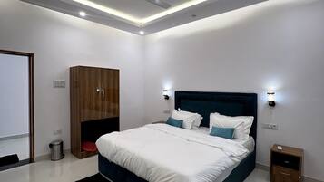 A modern bedroom with a large bed, a ceiling fan, recessed lighting, a wardrobe, and a nightstand.