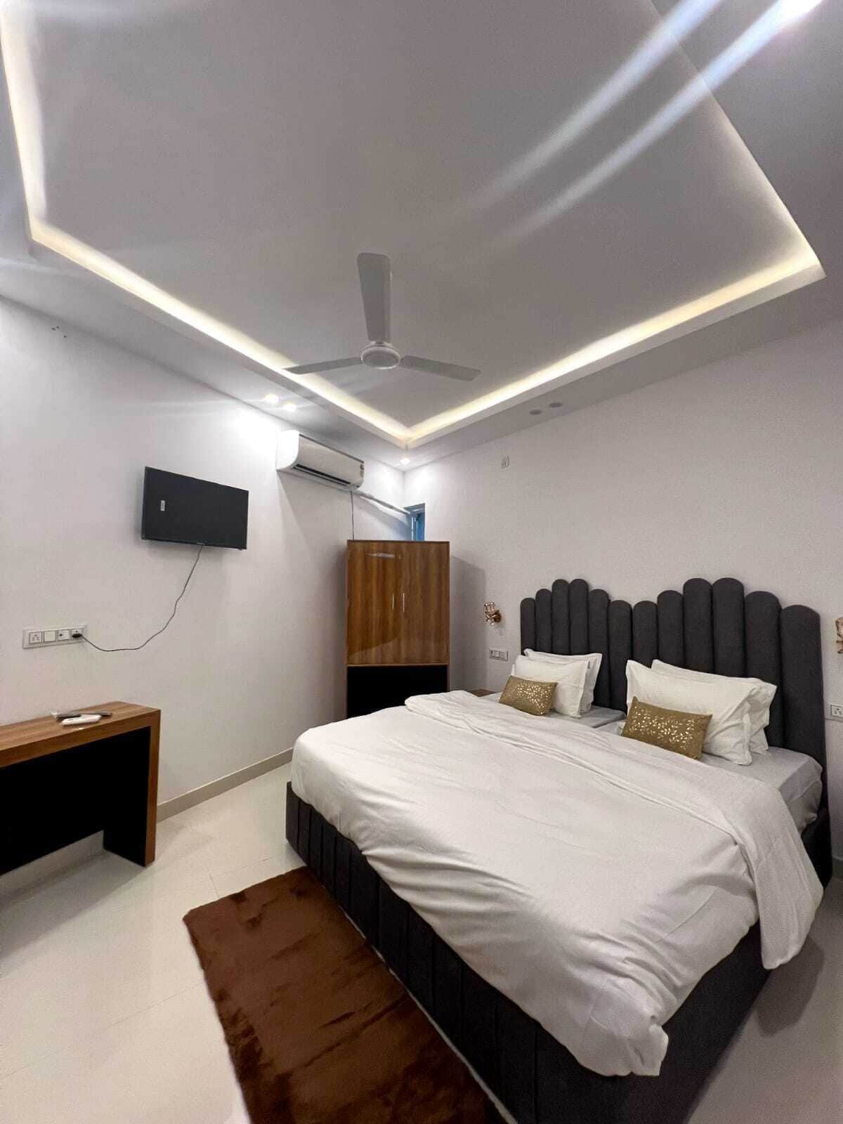 A modern bedroom with a bed, bedside tables, a TV, and a ceiling fan.