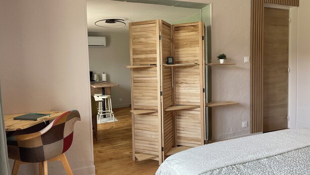 A room with a bed, a desk with a chair, a wardrobe, and a small plant on a shelf. - Gîte PREY DES VOSGES (Prey)