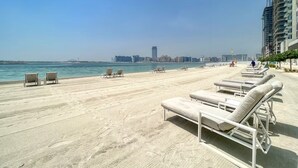 A beachside promenade with lounge chairs and a view of the sea and city skyline. - Beach Vista Residences - Dubai Harbour (Dubai)