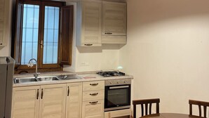 Une cuisine avec des poutres en bois, une cuisinière à gaz, un four encastré et une table à manger avec des chaises.