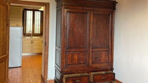 Une pièce spacieuse avec une armoire en bois, un sol carrelé et une cuisine à l’arrière-plan.