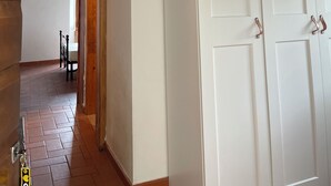 Une pièce aux murs blancs, avec un plafond en bois et une porte dotée de poignées en métal.