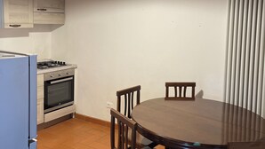 Une cuisine avec une table de salle à manger ronde, des chaises en bois, un poêle et un luminaire suspendu.