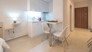 Een moderne keuken met witte kasten, een aanrecht en twee witte stoelen.