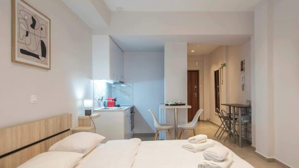Een hotelkamer met een bed, een bureau, een stoel, een klein tafeltje en een schilderij aan de muur.