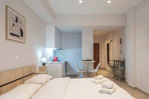 A hotel room with a bed, a desk, a chair, a small table, and a painting on the wall. - Koukaki Sofia's Apartment, 3-Min Walk to the Acropolis (Athina)