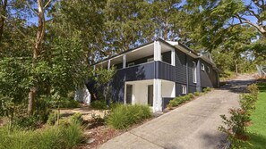 A modern two-story house with a covered porch, surrounded by lush greenery and trees. - Mackaren's Lodge - Chic (MACMASTERS BEACH)