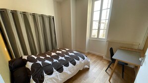 A bedroom with a bed, a desk, and a window. - Logis du 96 (Angoulême)