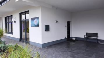 A modern building with a covered outdoor area, a bench, and a door.