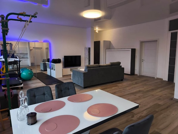 Un salón amplio con un sofá gris, un televisor y equipo de ejercicio.