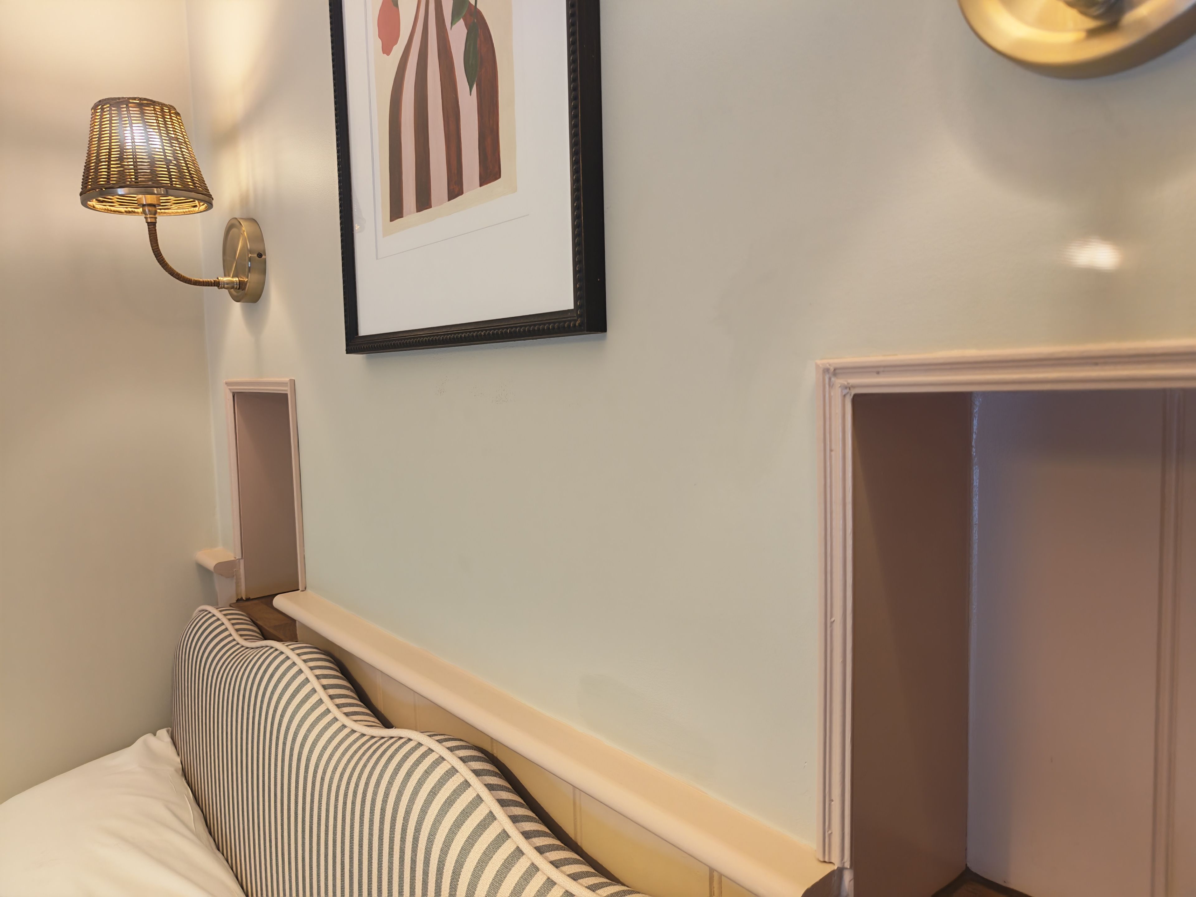 Un dormitorio con una cama, una lámpara de pared y un cuadro enmarco.