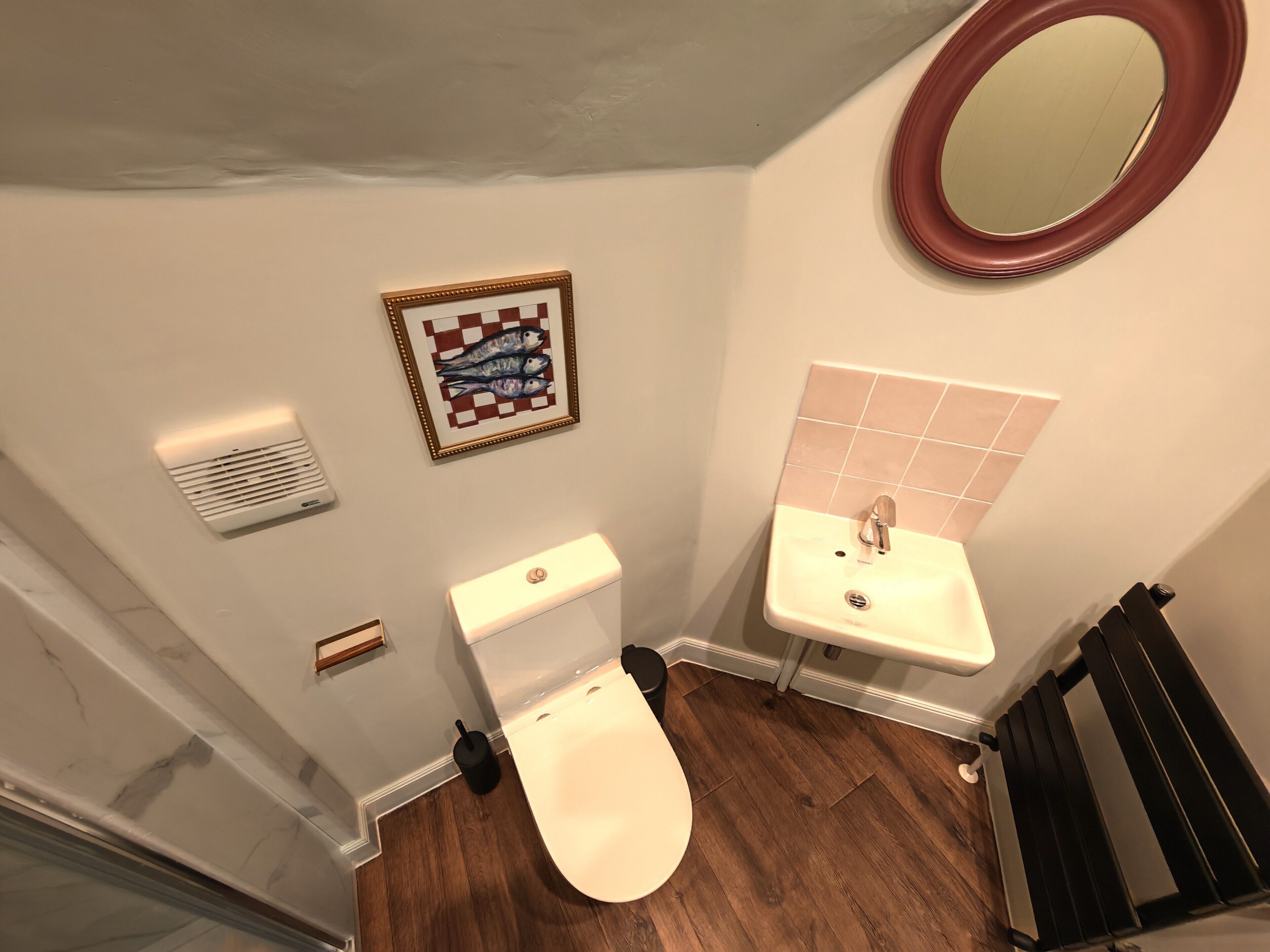 A bathroom with a toilet, sink, and mirror.