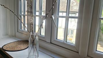 A window with a clear view of the outside, a vase with branches, and two woven mats on the sill.