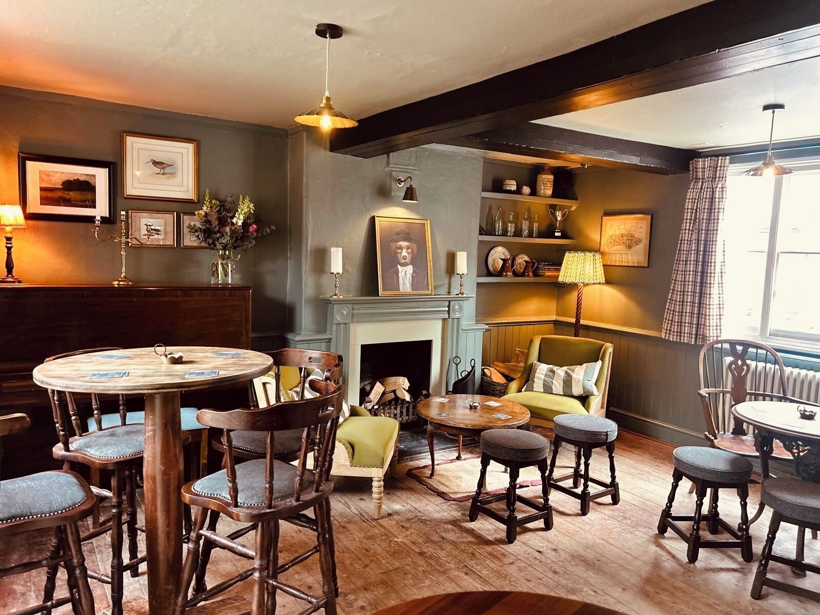 A cozy room with a round table, wooden chairs, a fireplace, and a bookshelf.