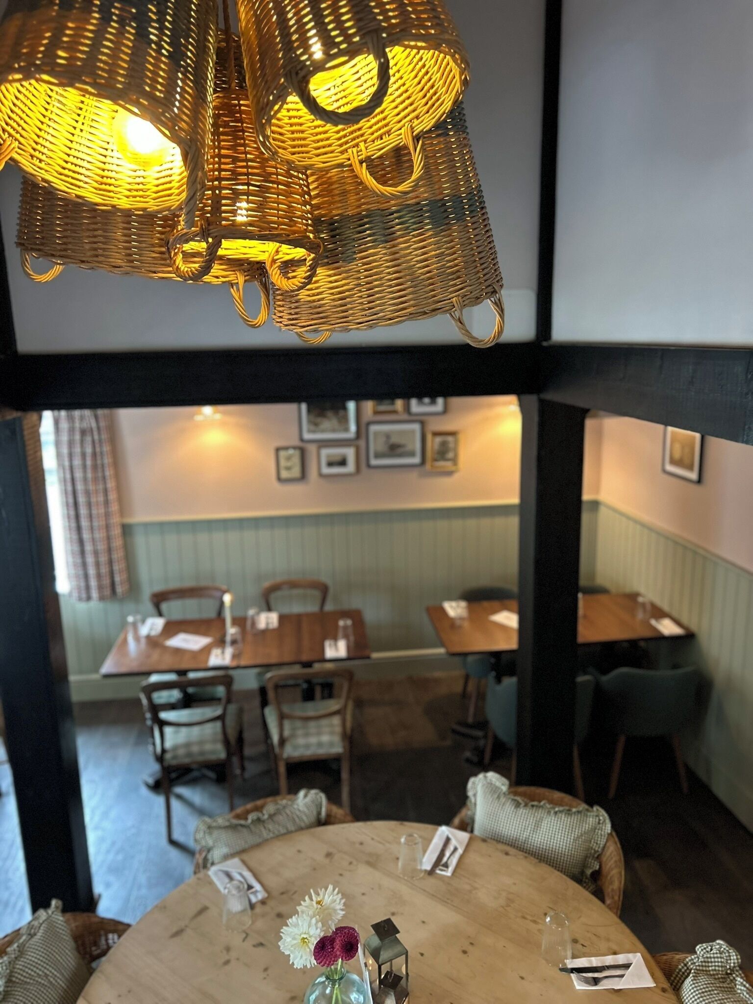 Un coin repas avec une table ronde, des chaises et un luminaire suspendu en osier.